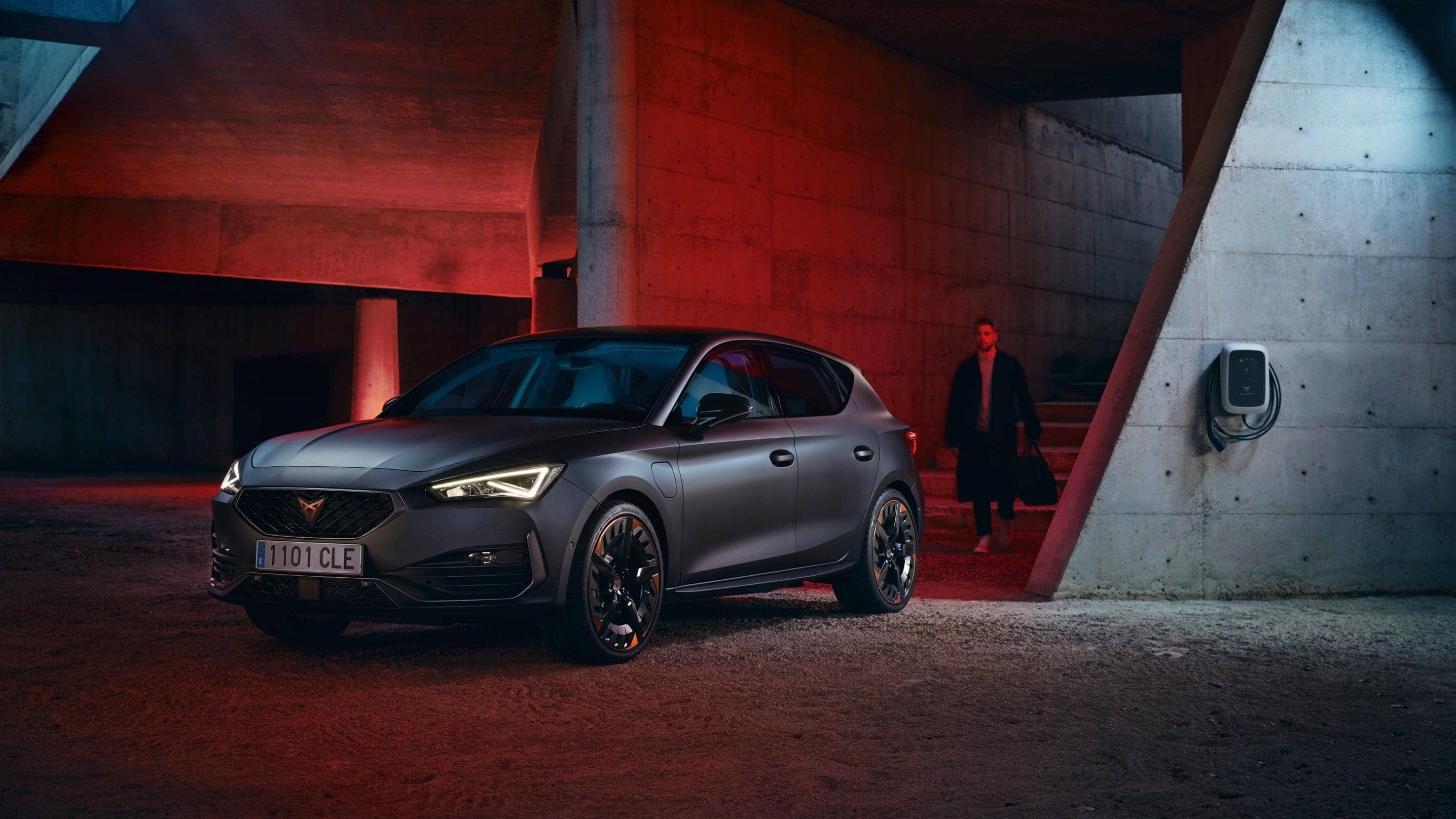 Nový kompaktní sportovní vůz CUPRA Leon 5D ehybrid v barvě magnetic šedá matná, boční pohled při nabíjení 