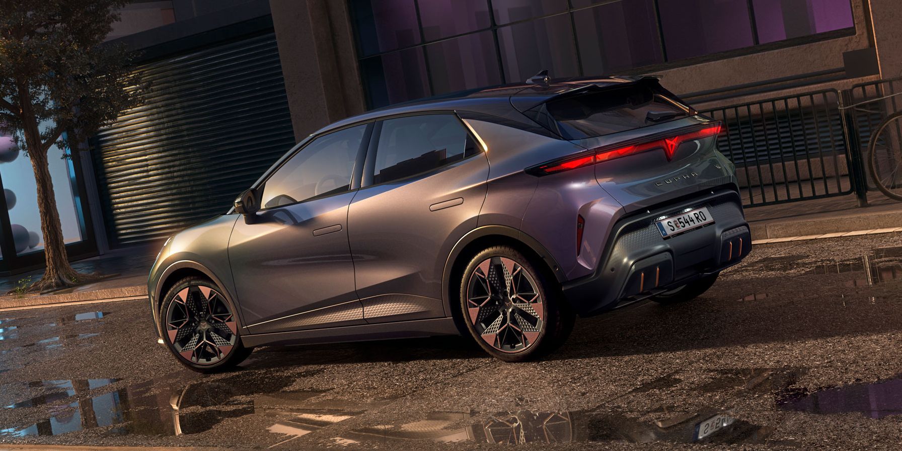 Detailní pohled na zadní část vozu CUPRA Raval VZ v barvě Plasma s 19palcovými koly, zaparkovaného v městské ulici v nočních hodinách.