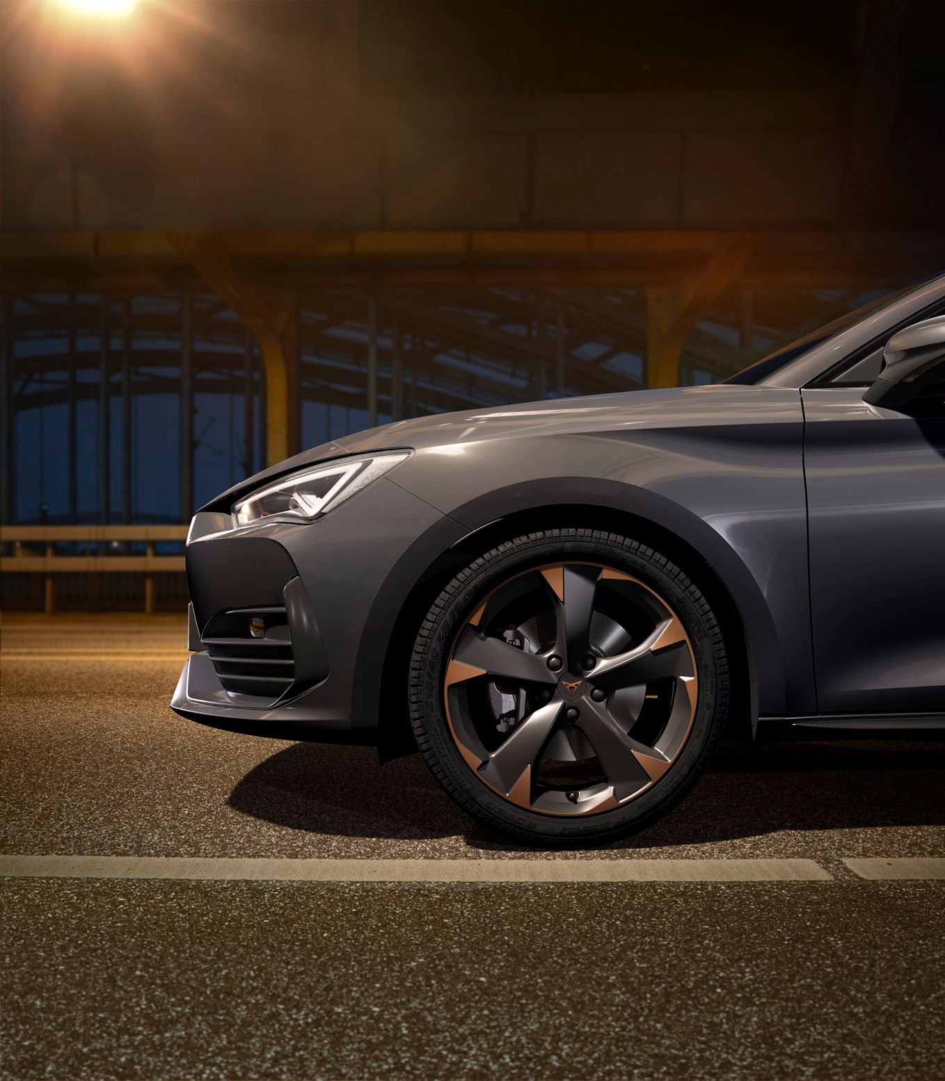 Nový kompaktní sportovní vůz CUPRA Leon 5D ehybrid v barvě magnetic šedá matná, boční pohled zpředu při nabíjení