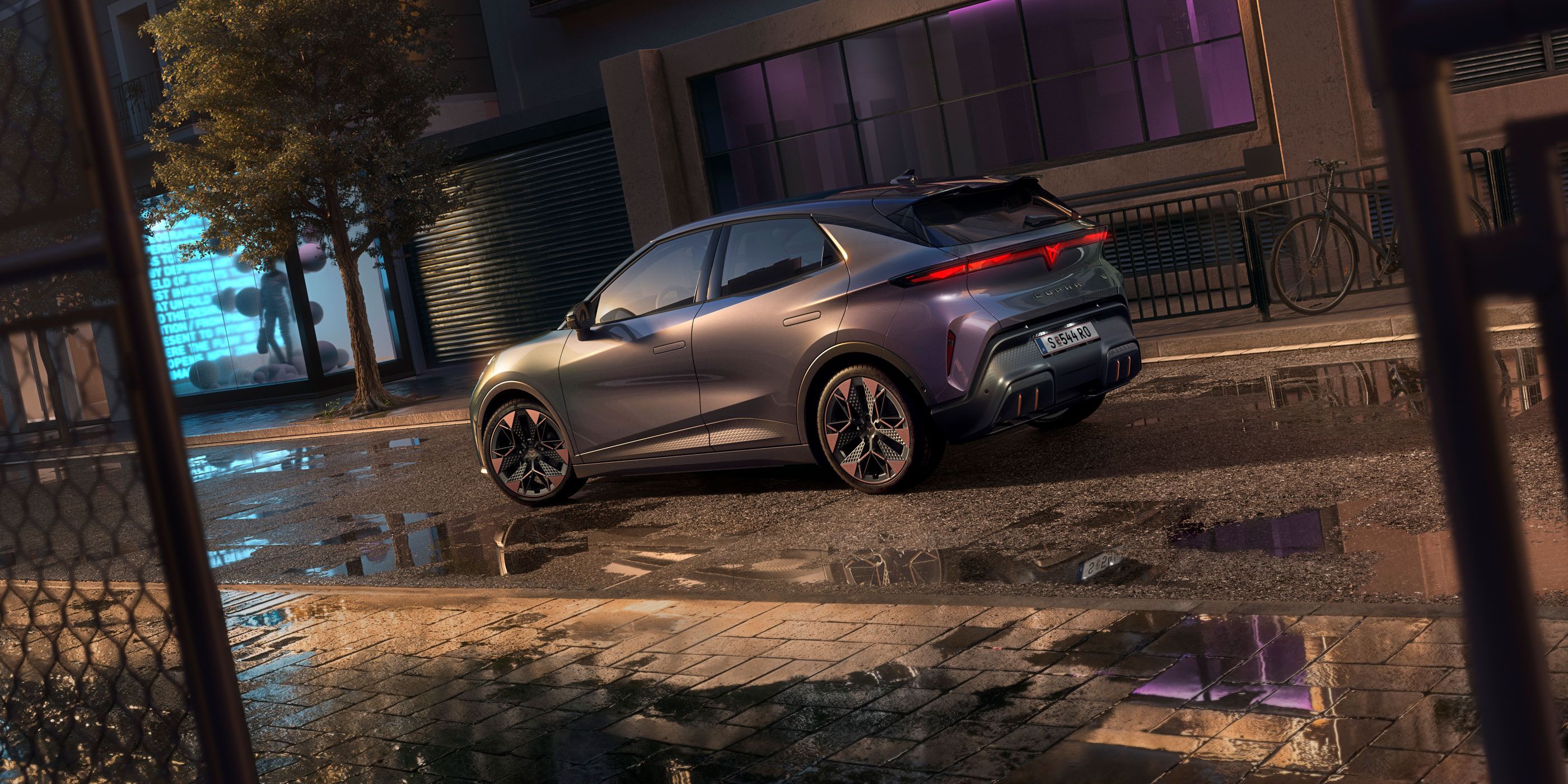 Nahaufnahme der Heckansicht des CUPRA Raval VZ in Plasma mit 19-Zoll-Felgen, geparkt auf einer städtischen Straße bei Nacht.
