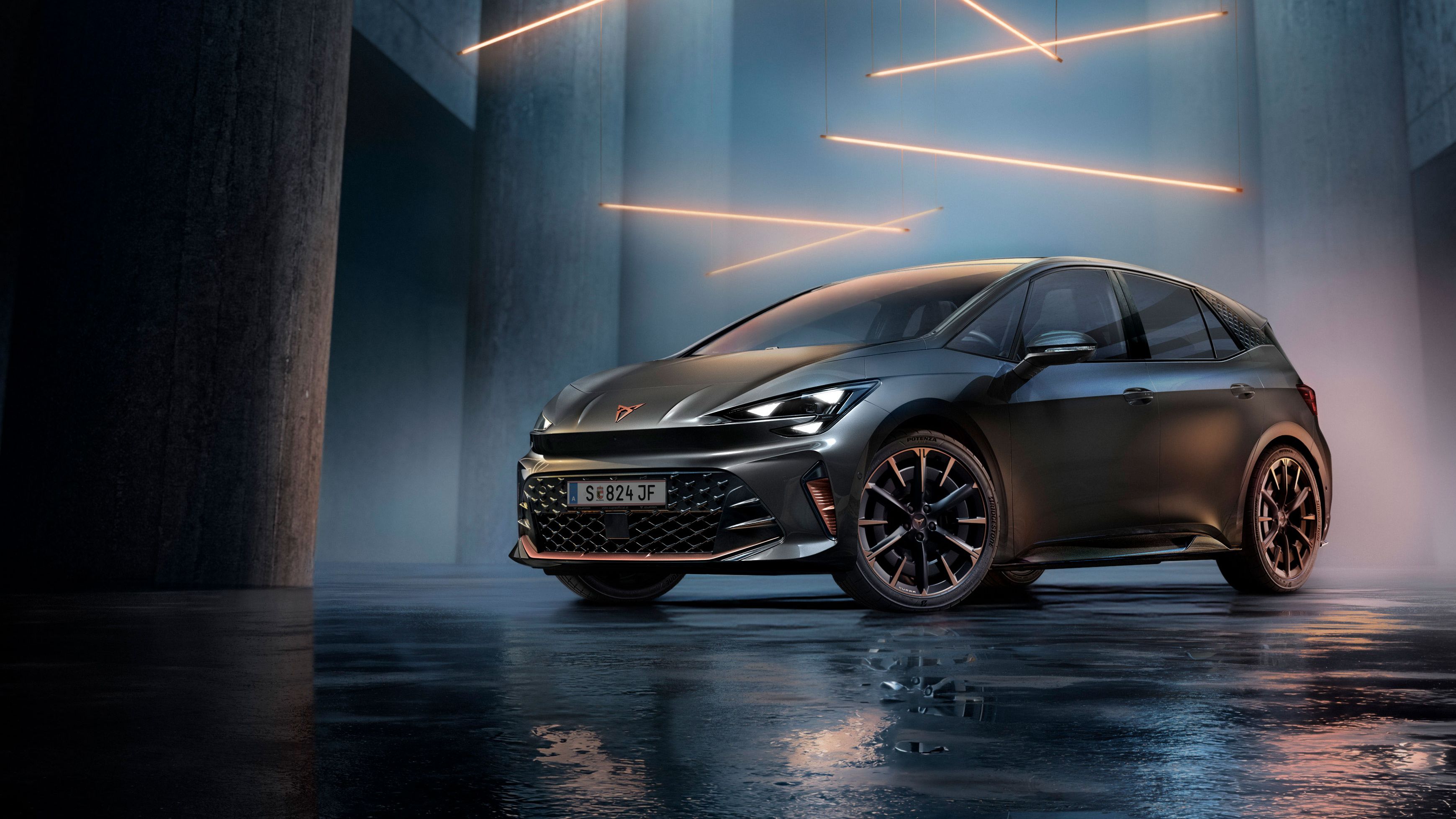 Ein grauer CUPRA Born steht in einer modernen, dunklen Umgebung mit vertikalen Säulen und leuchtenden LED-Streifen. Der Boden ist glänzend und reflektiert das Fahrzeug sowie die Beleuchtung. Das Auto wirkt kraftvoll und elegant.