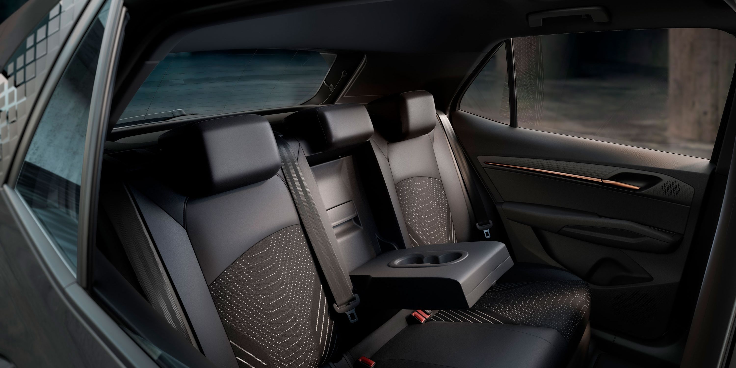 Auf dem Bild ist die Rücksitzbank des CUPRA Born zu sehen. In der Mitte befindet sich eine ausgeklappte Armlehne mit zwei Getränkehaltern.