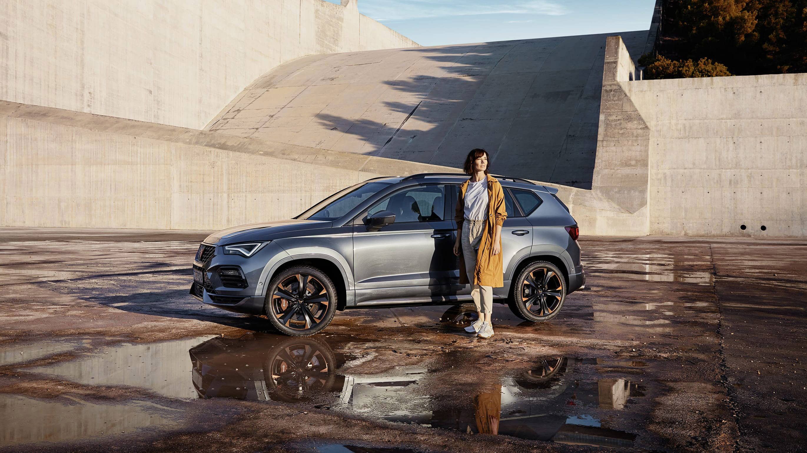 CUPRA Ateca 2020 v barvě rodium šedá boční pohled a žena stojící před vozem